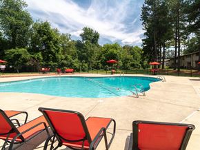 Greensboro apartment for rent - A pool with red chairs and trees in the background.