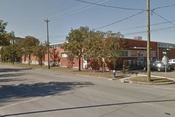 Houston apartment for rent - A street view with a red brick building on the right and a tree in the middle of the road.