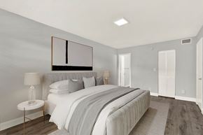 N. Miami apartment for rent - A bedroom with a large bed and a lamp on a side table.