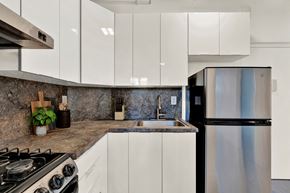 Miami Beach apartment for rent - A modern kitchen with a stainless steel refrigerator and a granite countertop.