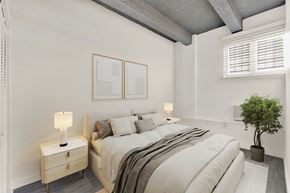 Miami Beach apartment for rent - A bedroom with a large bed, a nightstand with a lamp, and a potted plant.