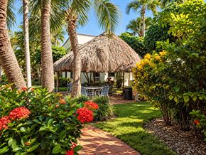 Miami apartment for rent - A garden with a thatched roof and a table and chairs.
