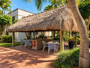 Miami apartment for rent - A thatched roof pavilion with a brick patio and white chairs.