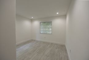 Miami apartment for rent - a bedroom with white walls and wood floors and a window