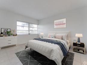 Hialeah apartment for rent - A bedroom with a large bed and a white dresser.