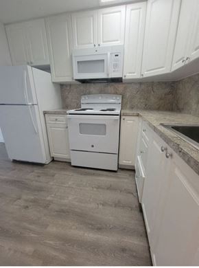 Homestead apartment for rent - a kitchen with white appliances and white cabinets