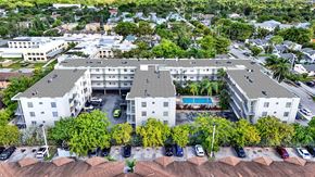 N. Miami apartment for rent - An aerial view of a white apartment complex with a pool and cars parked in the driveway.