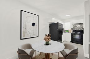 N. Miami apartment for rent - A modern kitchen with a round table and chairs, a fridge, and a painting on the wall.