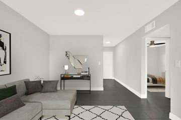 N. Miami apartment for rent - A living room with a grey couch and a black and white rug.