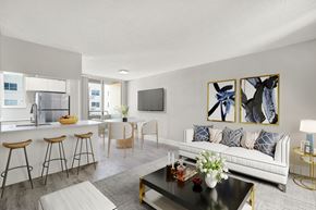 Miami Beach apartment for rent - A modern living room with a white couch, a coffee table, and a kitchen area in the background.