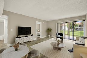 Fort Pierce apartment for rent - A living room with a white sofa, a white coffee table, and a flat screen TV.