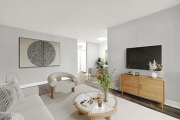 N. Miami Beach apartment for rent - A modern living room with a white sofa, a wooden coffee table, and a large abstract painting on the wall.