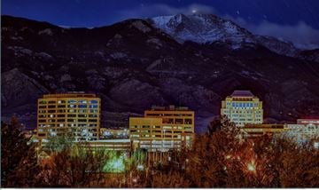 Colorado Springs apartment for rent - A cityscape at night with buildings and a mountain in the background.