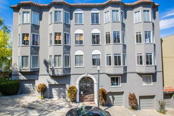 San Francisco apartment for rent - A grey building with a red tile roof and a car parked in front.