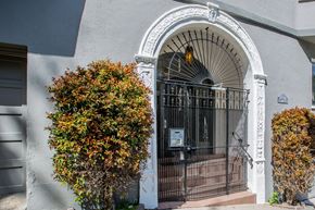 San Francisco apartment for rent - A white arched doorway with a black gate and a small tree to the left.
