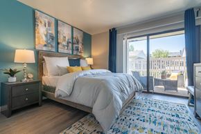 Redlands apartment for rent - A bedroom with a large bed and a view of a fence and trees outside the window.