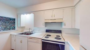 Mission apartment for rent - a kitchen with white cabinets and black appliances and a sink