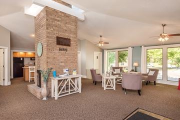 Olathe apartment for rent - a living room with a fireplace and a dining room with chairs and tables