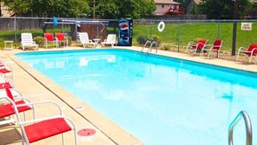 Olathe townhouse for rent - a swimming pool with red chairs around it