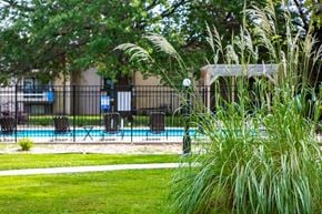 Lee's Summit apartment for rent - a pool with a fence and chairs in a yard