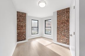 Brooklyn apartment for rent - A room with a brick wall and a window overlooking a cityscape.