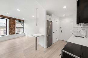 Brooklyn apartment for rent - A modern kitchen with a brick wall and a large window.