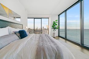 Chicago apartment for rent - A bedroom with a large bed and a view of the city.