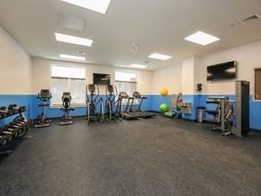 Elmsford apartment for rent - a gym with cardio equipment and weights on the floor