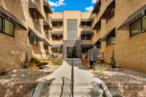 Denver apartment for rent - A courtyard surrounded by buildings with a metal bench in the middle.