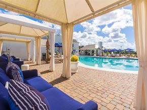 Gulf Shores apartment for rent - A poolside area with blue loungers and a white canopy.