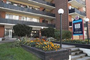 Toronto apartment for rent - an apartment building with a sign in front of a flower garden