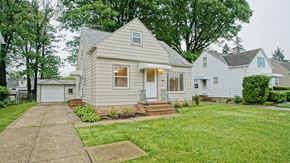 Mayfield Heights apartment for rent - A house with a grey roof and a white door is surrounded by a green lawn.