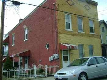 Clairton apartment for rent - a red and yellow building with a car parked in front of it