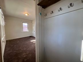 Homestead apartment for rent - A room with a brown carpet and a white wall with a row of hooks.
