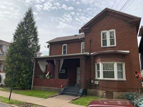 Homestead apartment for rent - A red brick house with a white window and a black door.