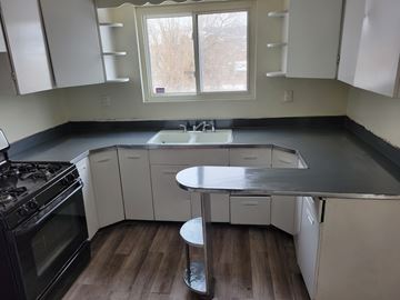 Homestead apartment for rent - A kitchen with white cabinets and a black stove top oven.