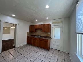Munhall house for rent - an empty kitchen with wooden cabinets and tile flooring