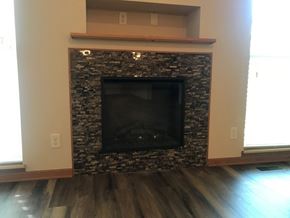Lincoln house for rent - A stone fireplace with a wood mantle and a black screen.