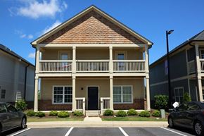 Kennesaw apartment for rent - a yellow house with a balcony and cars parked in front of it