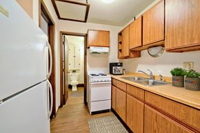 Grand Forks apartment for rent - a kitchen with white appliances and wooden cabinets and a door to the bathroom