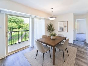 Levittown apartment for rent - A dining room with a table and chairs and a view of a green lawn outside.