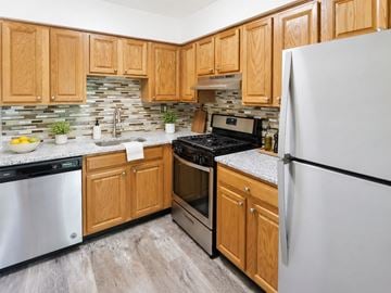 Levittown apartment for rent - A kitchen with wooden cabinets and a white refrigerator.