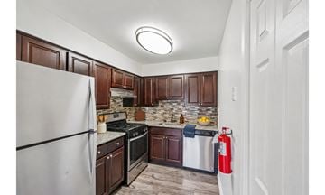 Levittown apartment for rent - A kitchen with a white refrigerator and dark brown cabinets.