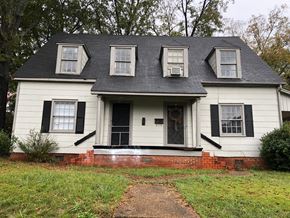 Talladega apartment for rent - A white house with black shutters and a brick base.