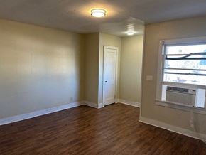 Talladega apartment for rent - A room with a wooden floor and a window with blinds.