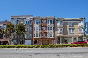 San Francisco apartment for rent - A row of three-story apartment buildings with balconies line a street.