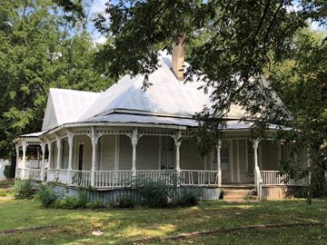 Talladega house for rent - A white house with a porch and a chimney.