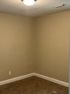 Talladega house for rent - A room with a carpeted floor and a light on the ceiling.