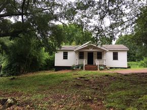 Talladega house for rent - a small white house with a yard and some trees