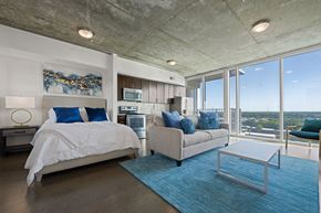 Charlotte apartment for rent - A bedroom with a large bed and a couch with a view of the city.